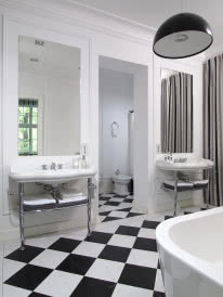 Mocnym punktem w jasnej łazience są klasycznie ułożone biało-czarne płytki