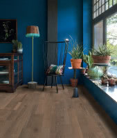 zestawienie podłogi drewnianej w mocnym wybarwieniu ze ścianą pomalowaną na nasycony odcień błękitu. Quick-Step
