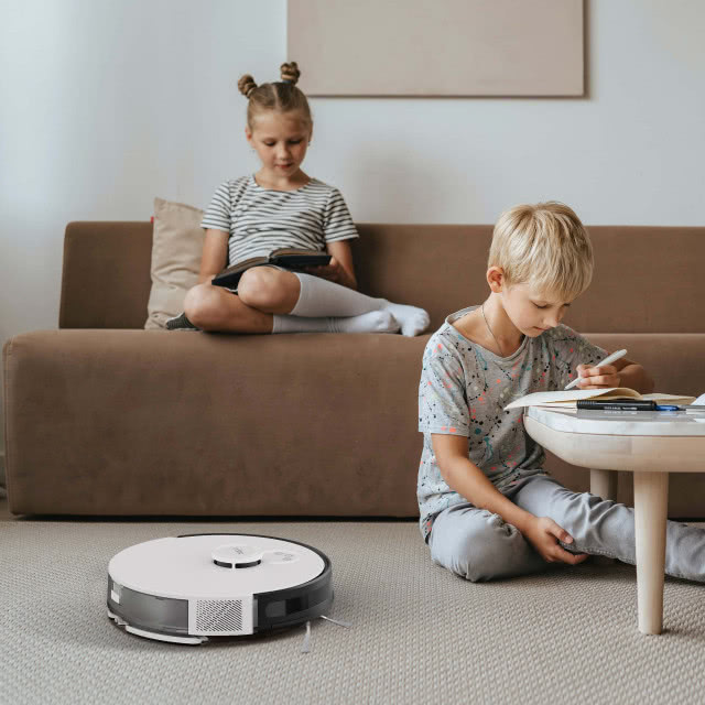 robot sprzątający, kanapa, stolik, chłopiec odrabia lekcje, dziewczynka czyta książkę, obrz, wykładzina