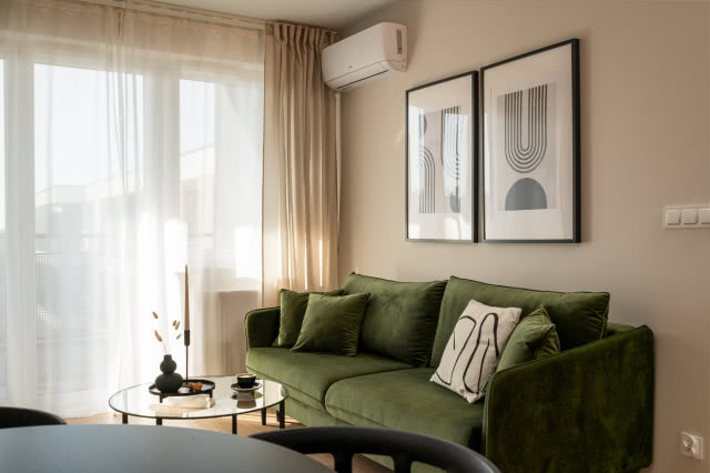 Beżowy salon z ciemnozieloną kanapą