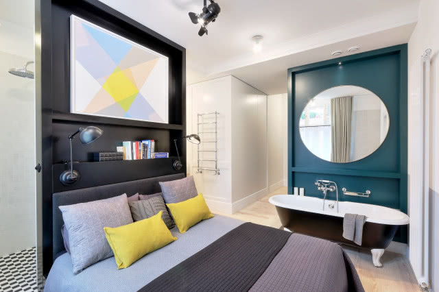 W sypialni obok łóżka stoi wolno stojąca, żeliwna wanna