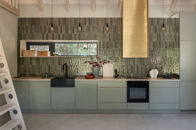 kuchnia, nad blatem zielone kafle, czarny zlew i złoty okap