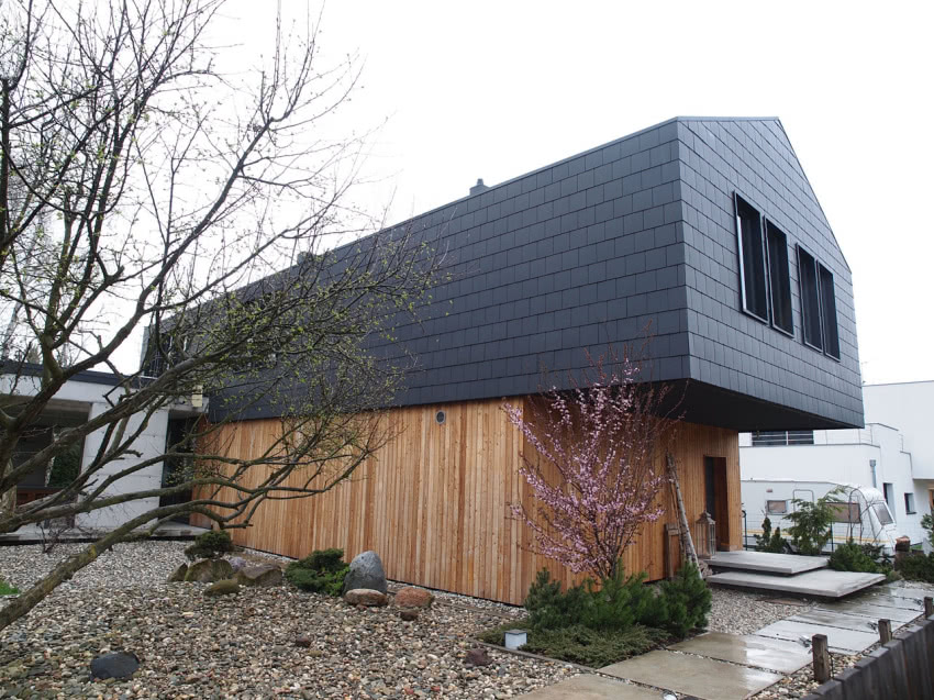 Kubiczną bryłę domu podkreśla elewacja z łupku i...