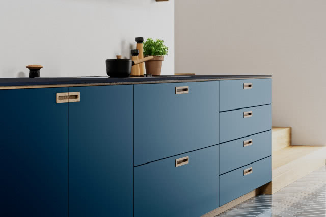 komoda z niebieskimi frontami, czarny blat, rondel, solniczka, zioła w doniczce