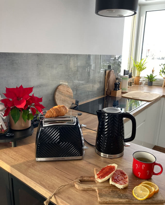 toster, czajnik elektryczny, gwiazda betlejemska, płyta grzewcza, drewniany blat kuchenny, kubek z kawą, pieczywo z dżemem, cytryna