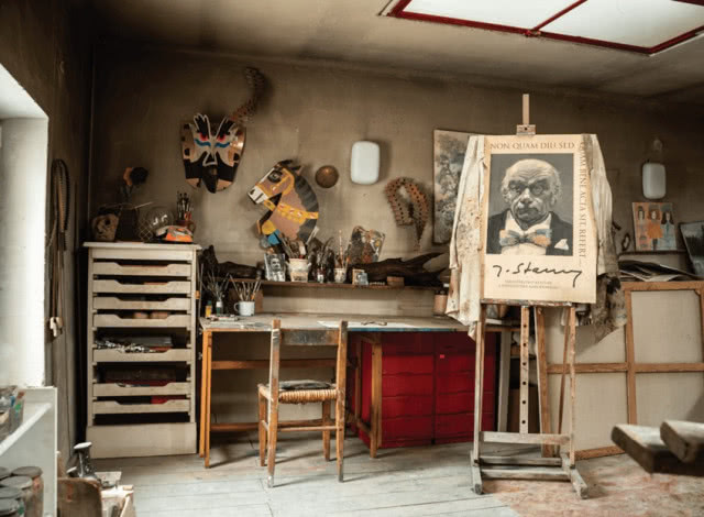 pracownia ze zdjęciem mężczyzny na sztalugach, biurko i krzesło