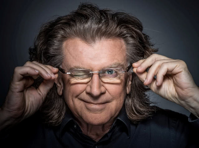 mężczyzna z burzą włosów w okularach