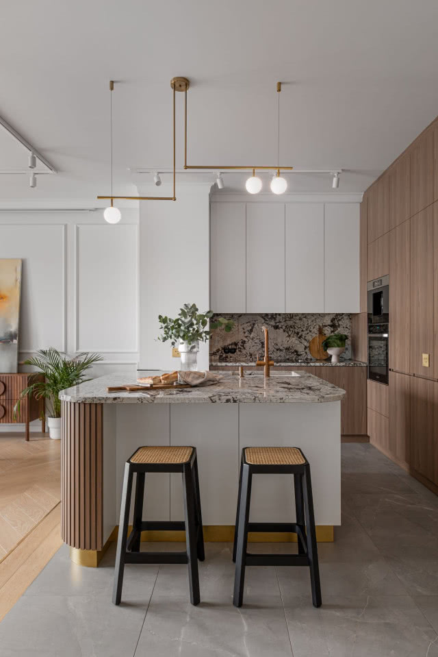 Biała kuchnia z dodatkiem drewna i hokerami z plecionki wiedeńskiej