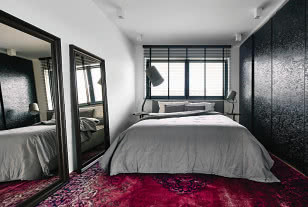 W sypialni gospodarzy duże, oparte o ścianę lustra efektownie powiększają wnętrze.