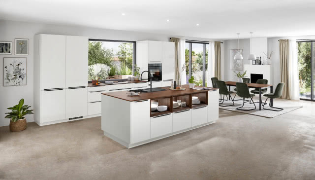 białe meble kuchenne, wyspa kuchenna z drewnianym blatem, duży stół z krzesłami, duże okna, zasłony, obrazy