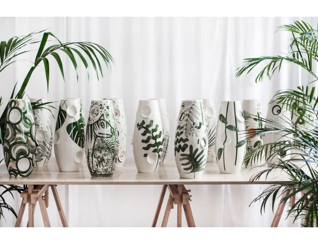 wazony na stole wśród roślin, zdobione motywem roślinnym