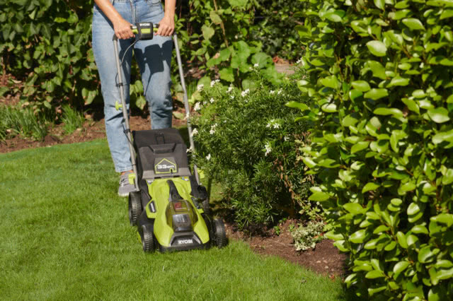 Mężczyzna używa kosiarki na akumulator RYOBI do cięcia brzegów trawnika