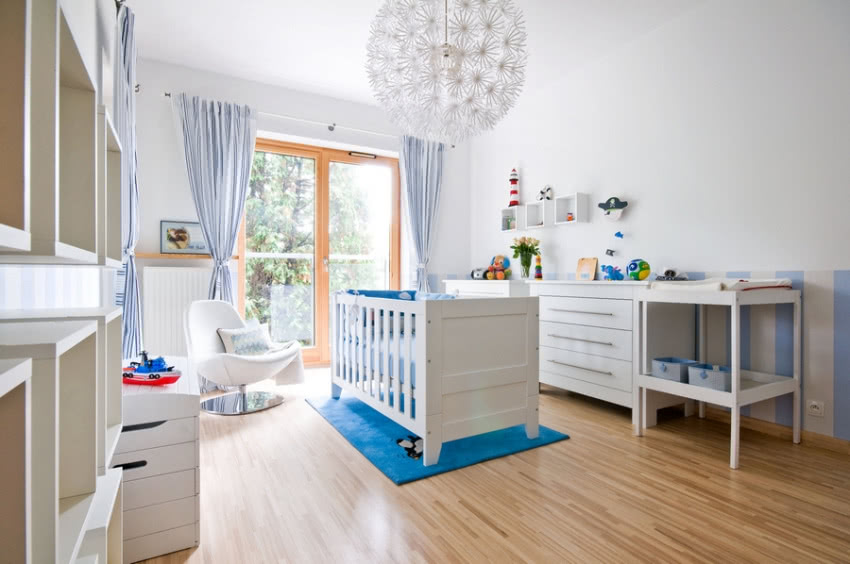 Biały pokój dziecięcy z niebieskimi akcentami.