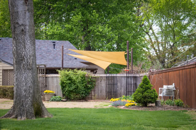 stary dom, płot z żerdzi i nowoczesny żagiel