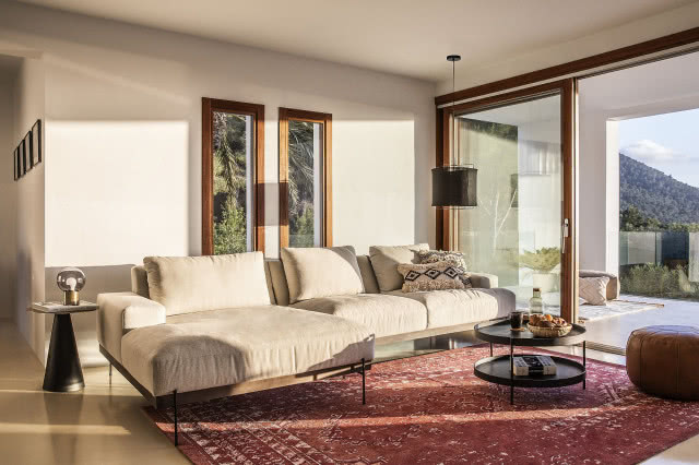 Westwing Collection w letnim wydaniu, narożnik w kolorze beżowym, dywan czerwony, stolik kawowy czarny-okrągły