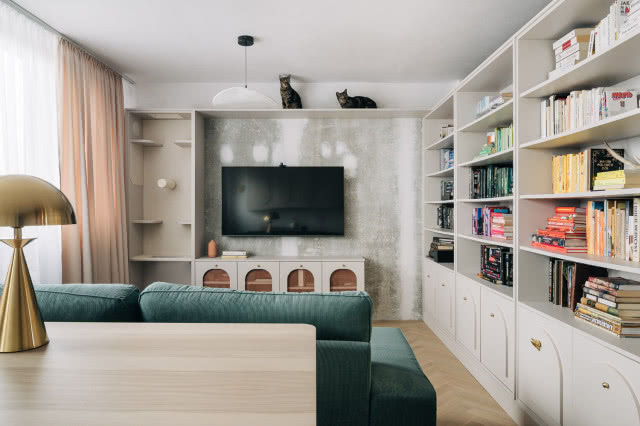 salon z zieloną kanapą i półką do chodzenia dla kotów