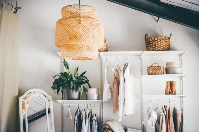 garderoba, zielone kwiaty w doniczkach, ubrania, wieszaki, lustro, koszyki wiklinowe , buty, lampa wisząca