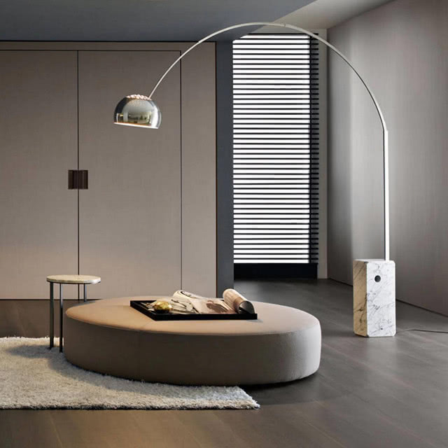 lampa w kształcie łuku oświetla duży okrągły puf