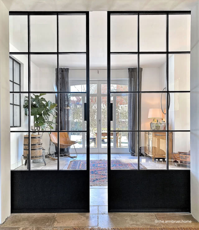 Drzwi przesuwne dwuskrzydłowe, salon, pokój wypoczynkowy, duży kwiat w doniczce, dywan, duże okno tarasowe, zasłony, komoda, oświetlenie biurkowe, krzesło