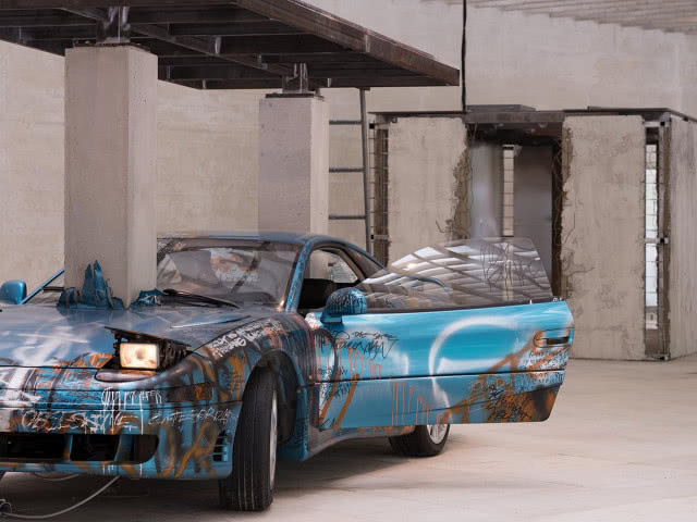 samochód pomalowany w graffiti ze słupem wbitym w maskę