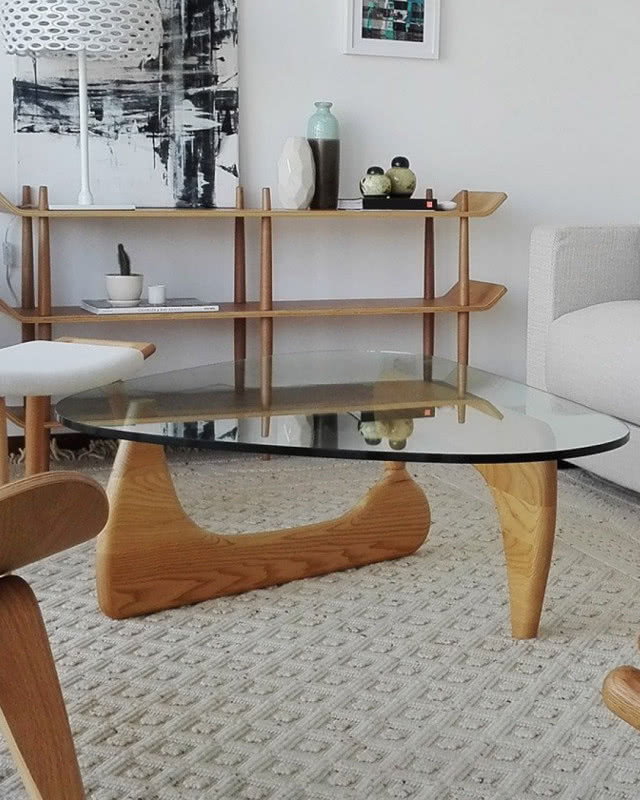 stolik z drewnianą podstawą i szklanym blatem stoi na środku dywanu