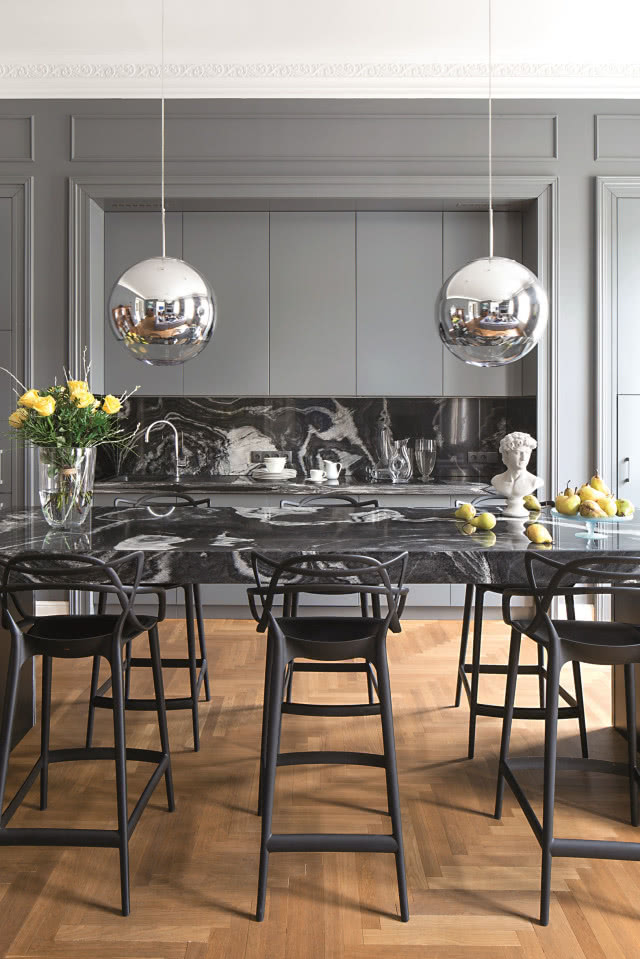 Srebrne lampy projektu Toma Dixona zawieszone w kuchni nad barkiem