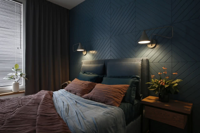 Zdjęcie łóżka w sypialni na tle granatowych ścian