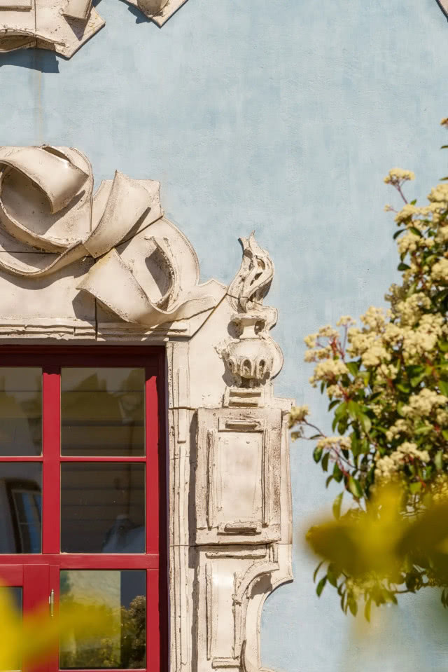 eklektyczne elementy na fasadzie i czerwona rama okna
