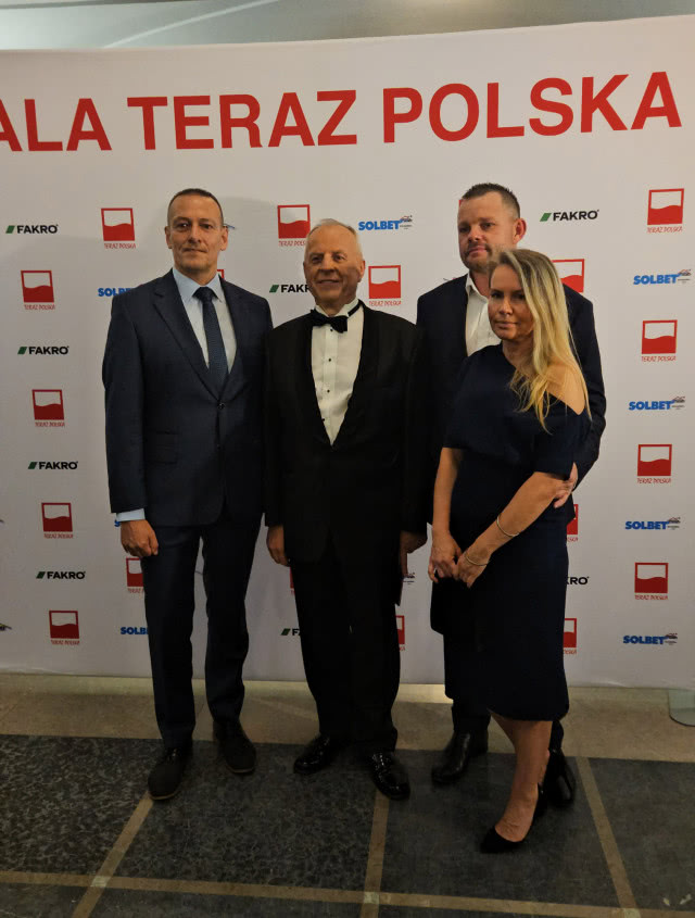 Uczestnicy Gali „Teraz Polska” pozują do zdjęcia na tle ścianki wydarzenia z logotypami partnerów, w tym FAKRO.