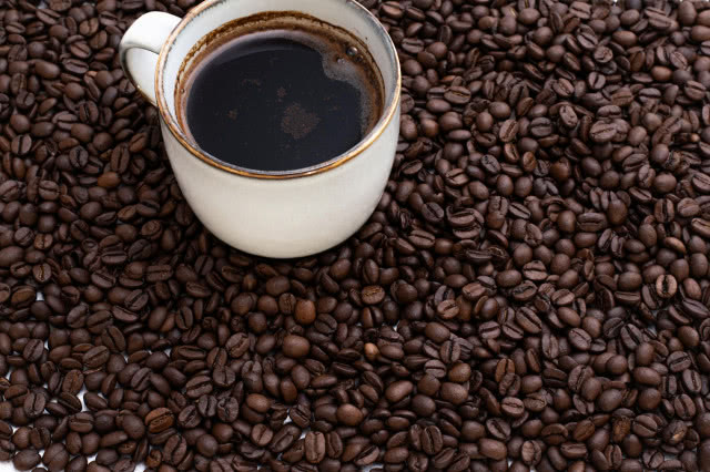 Kawa na tle świeżych ziaren kawowych