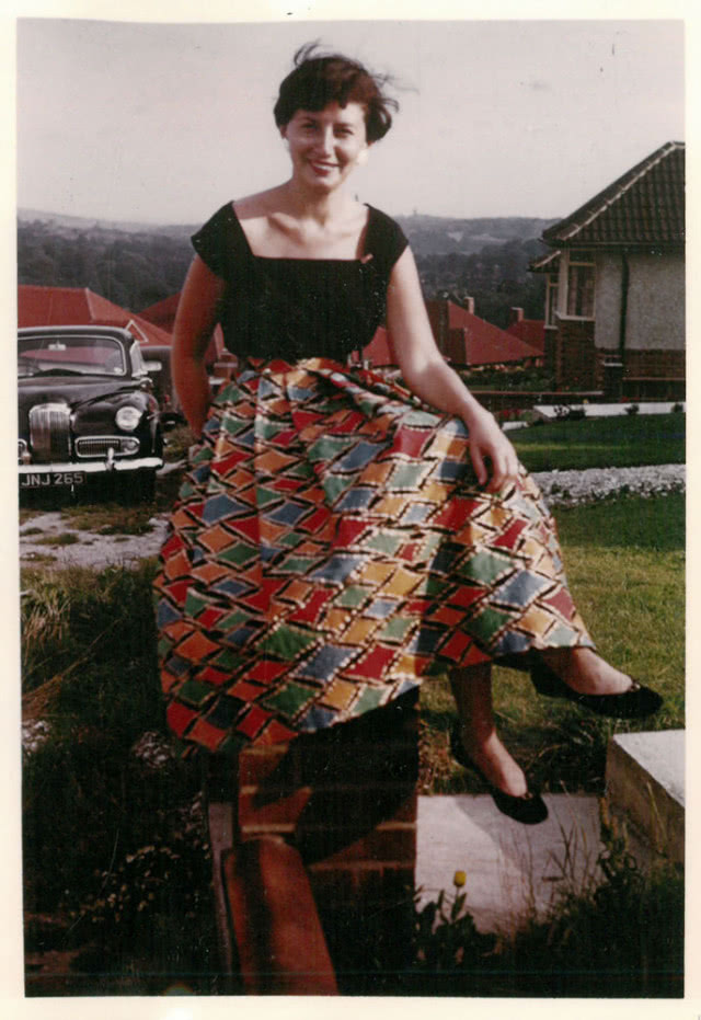 kobieta siedząca na murku w obszernej spódnicy