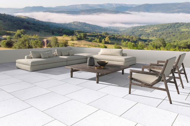 Nowoczesny taras wykończony jasnymi płytami Vestone, z minimalistycznymi meblami wypoczynkowymi