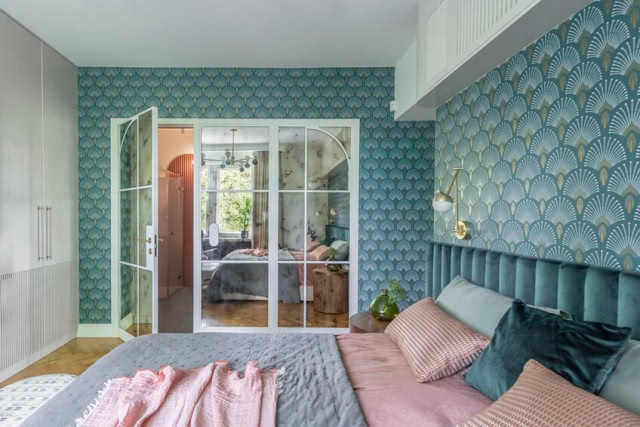 na pierwszym planie łóżko, w dali białe przeszklone w całości drzwi