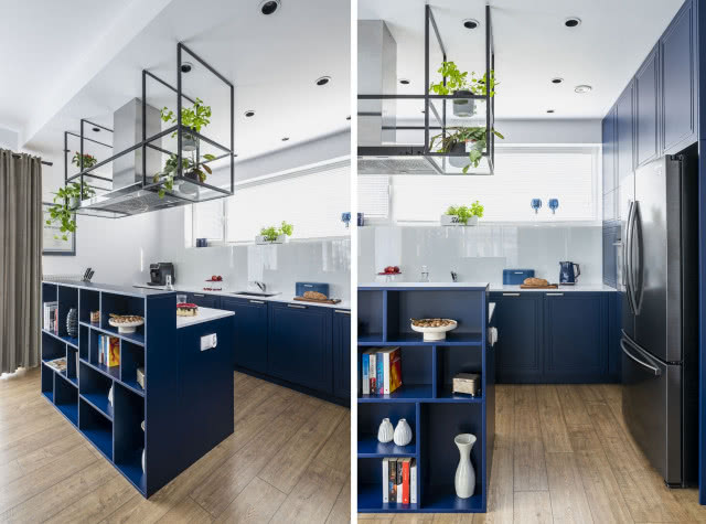 Aneks kuchenny w granatowym kolorze z wyspą i oświetleniem z roślinami