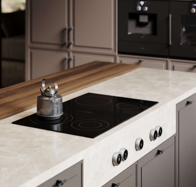 płyta elektryczna, czajnki, wyspa kuchenna, drewniany blat, szare fronty kuchenne, piekarnik, ekspres do kawy