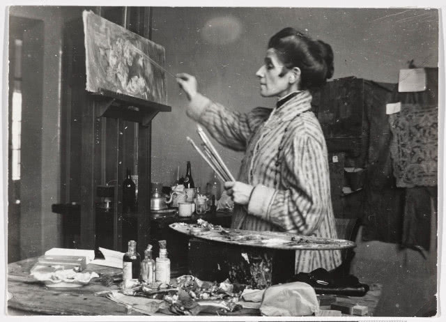 kobieta w fartuchu podczas malowania, ujęta z profilu