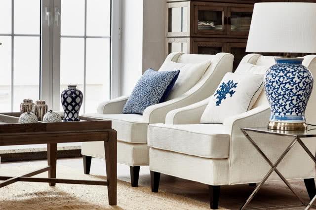 dwa fotele w zbliżeniu, poduszki i ceramiczna niebieska lampa