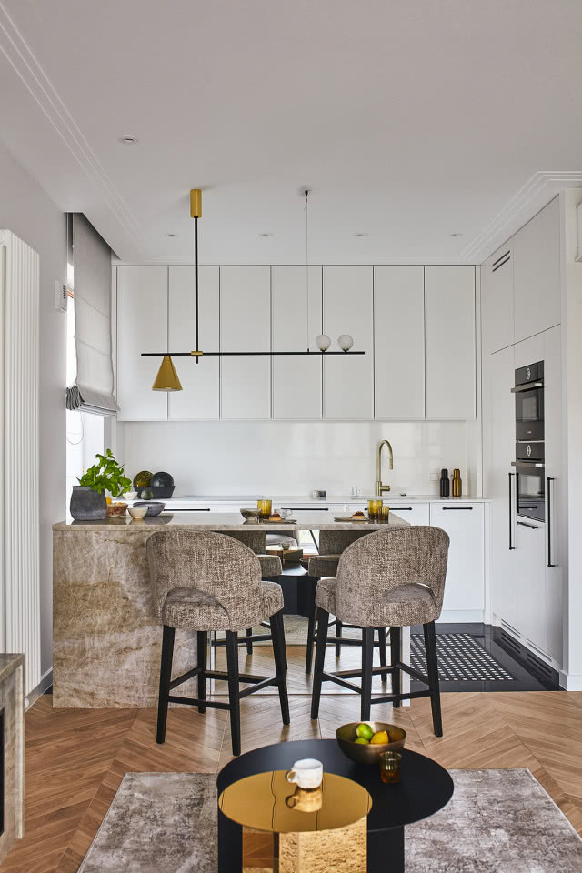 Biała kuchnia z wyspą i szarymi krzesłami