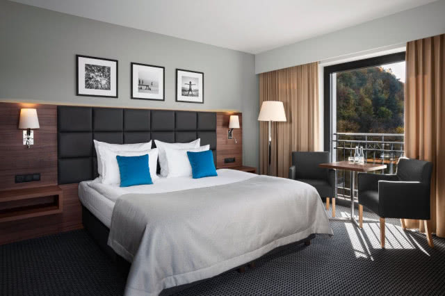 pokój w hotelu w szarościach, na łóżku dwie niebieskie poduszki