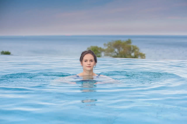 kobieta w basenie infinity, z którego rozciąga się widok