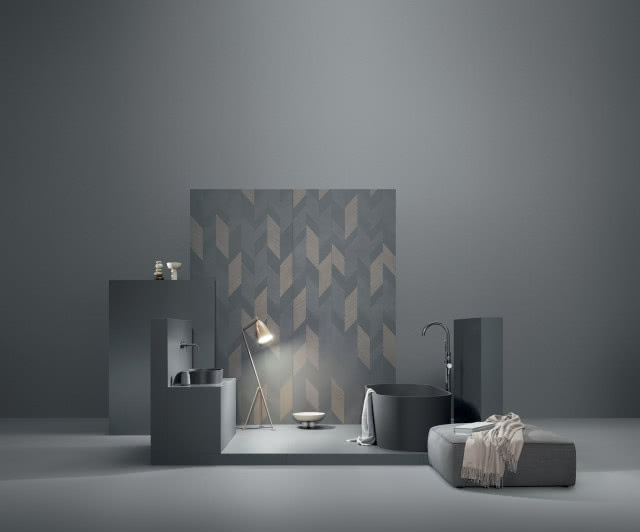 łazienka w kolorze grafitowym, wanna wolnostojąca, umywalka nablatowa, bateria podtynkowa, puf, koc, oświetlenie podłogowe
