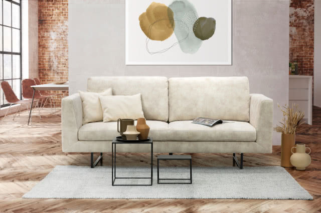 biała kanapa, dwa stoliki kawowe, dywan, cegła na ścianie, duży stół z krzesłami, obraz, wazon, jodełka na podłodze