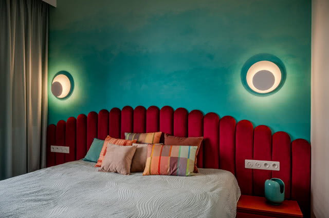 zielona ściana i tapicerowany zagłówek łóżka