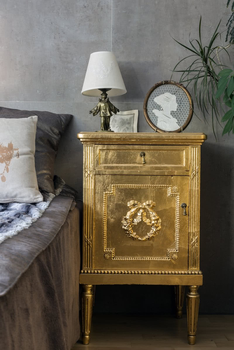 Szafka nocna pokryta płatkami złota wygląda...