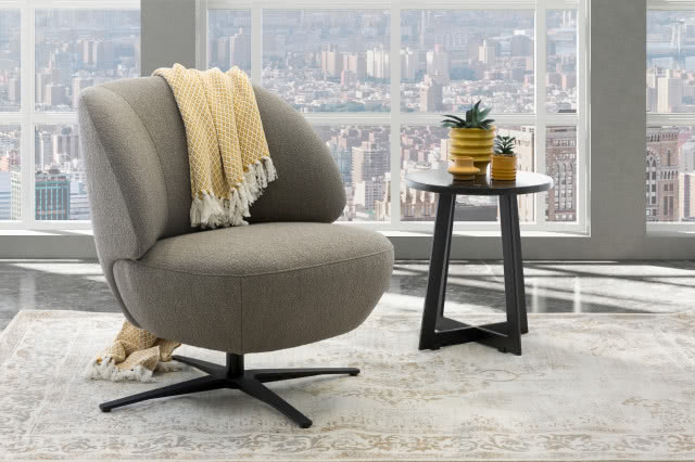 fotel, koc, duże okno. dywan, stolik kawowy, za oknem panorama miasta