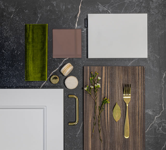 szare fronty kuchenne, ciemny drewniany blat kuchenny, złoty widelec, materiał butelkowa zieleń, złote uchwyty do frontów kuchennych