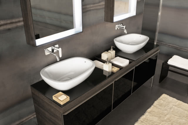 dwie białe umywalki, ciemne meble łazienkowe, mydło, ręczniki, baterie umywalkowe ścienne, dwa lustra, dywan