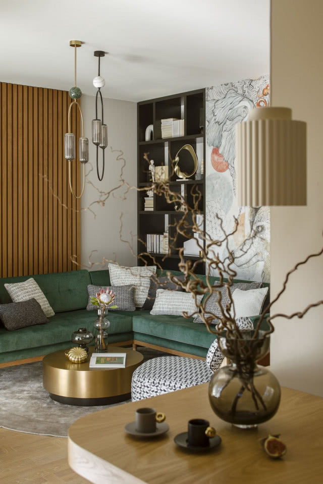 zielona sofa z obiciem z weluru w salonie i złoty stolik kawowy
