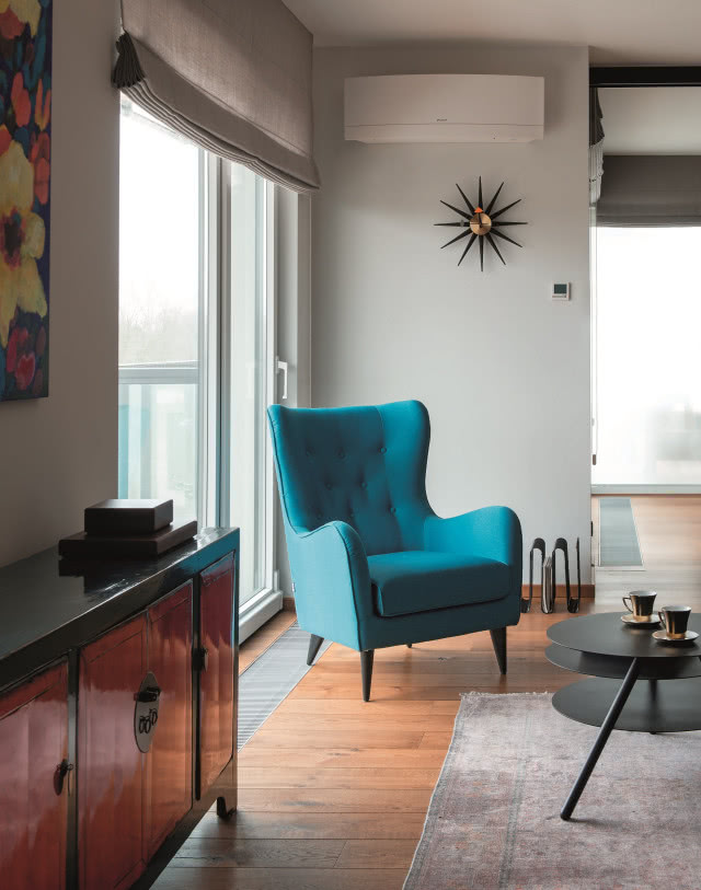 Turkusowy fotel uszak Sits i zegar marki Vitra.