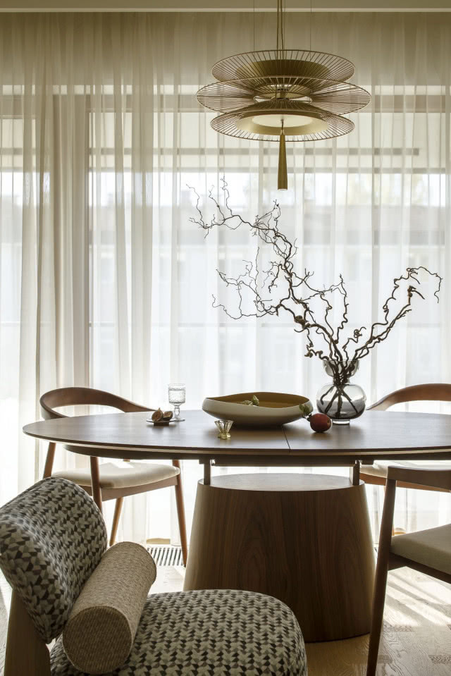 Kącik jadalniany w mieszkaniu z owalnym stołem i drewnianymi krzesłami